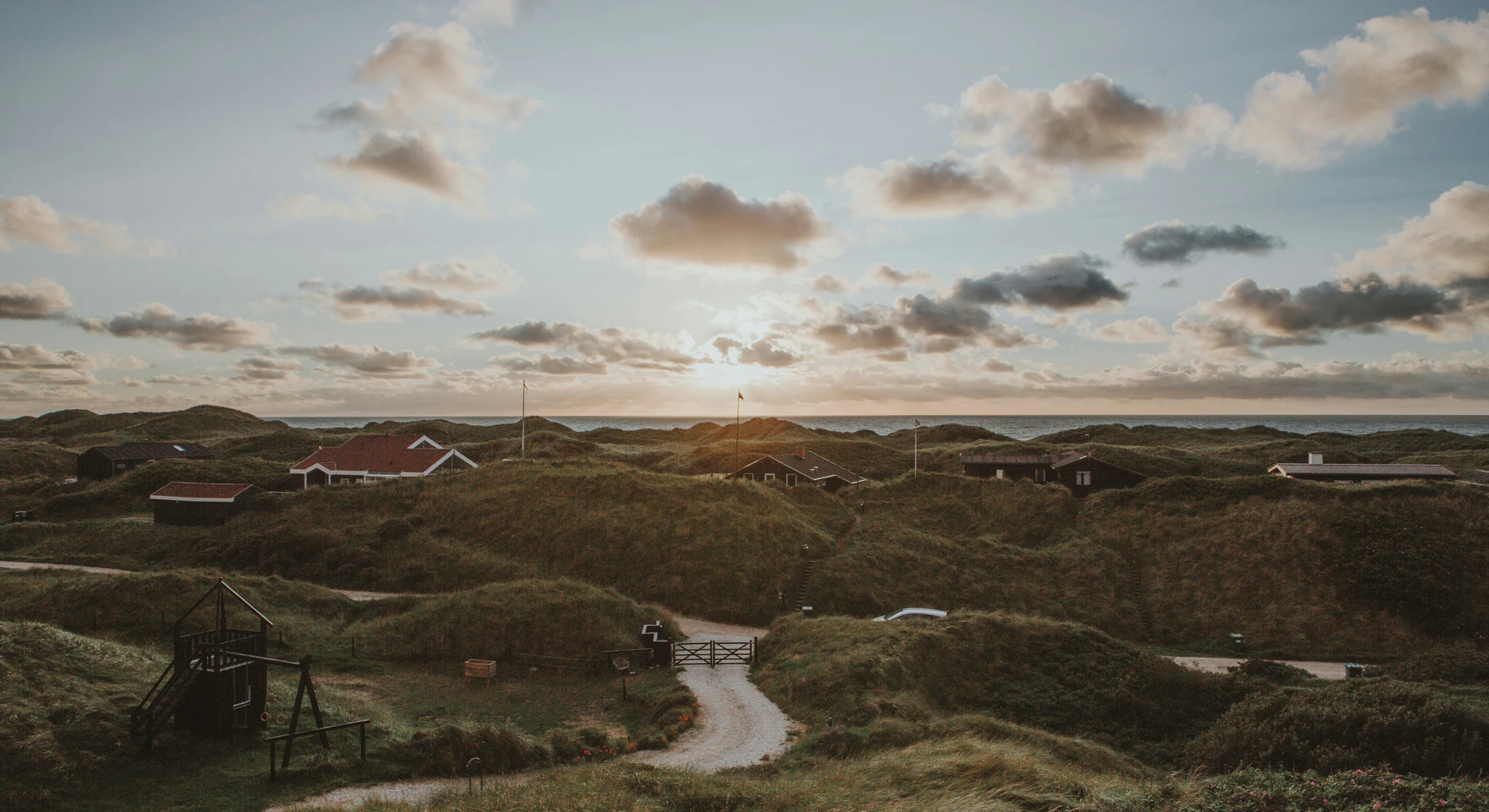 ett blåsigt skagen med små standhus och massa vass och sand en kväll